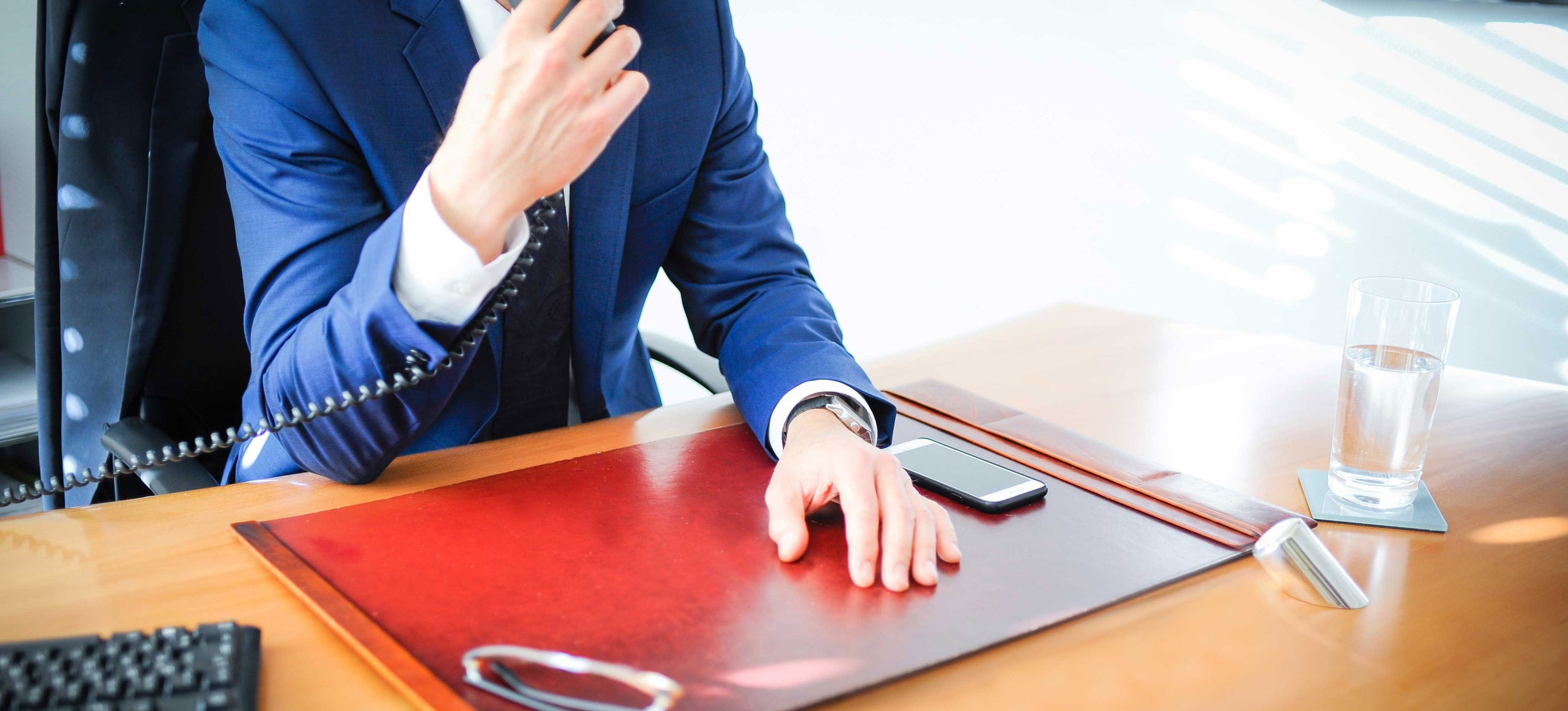 Anwalt an einem Schreibtisch mit der rechten Hand an einem Telefon
